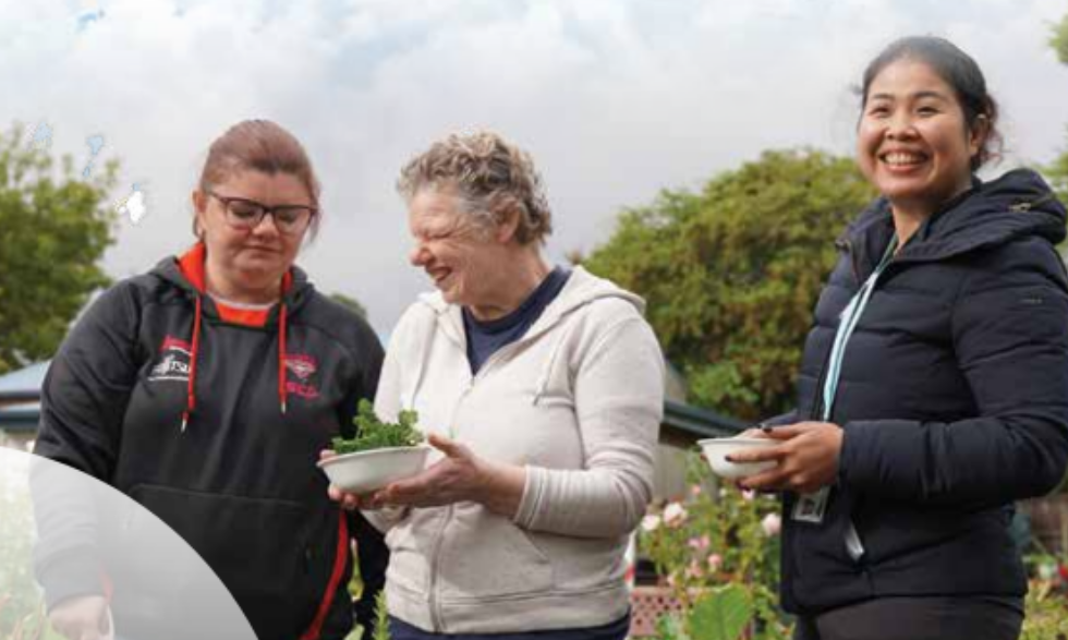 IMAGE: Two clients and a disability support worker out doors planting things in the garden