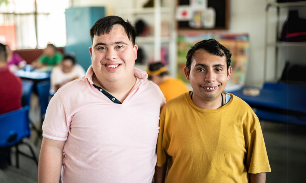 Image description: Two young people with disability standing side by side, smiling.