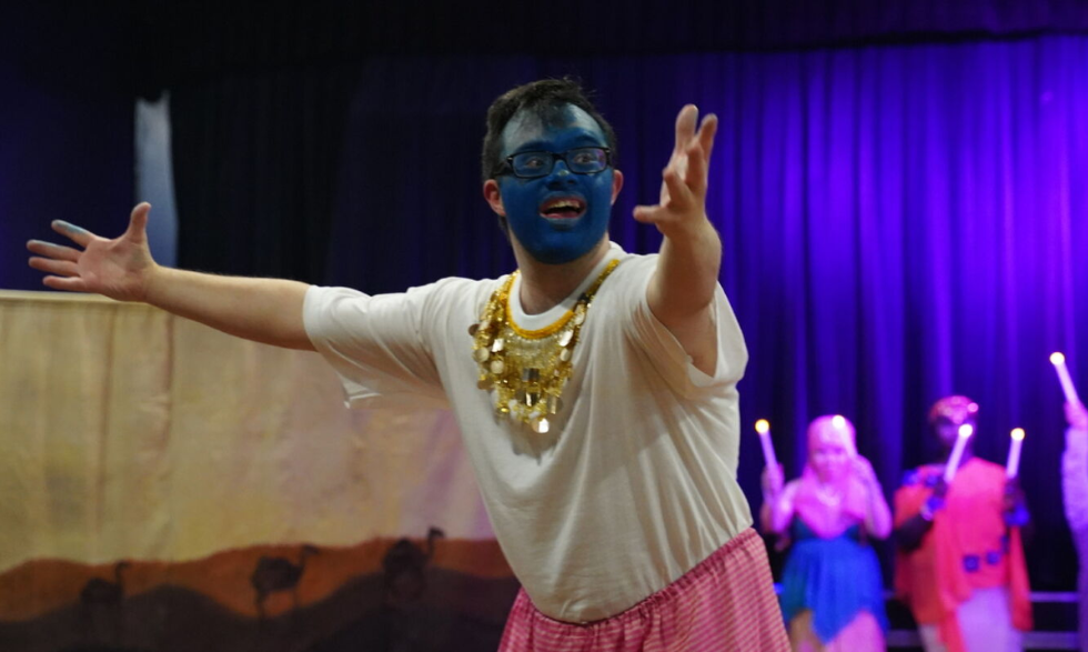 Client playing the Genie is performing to the audience in blue face paint