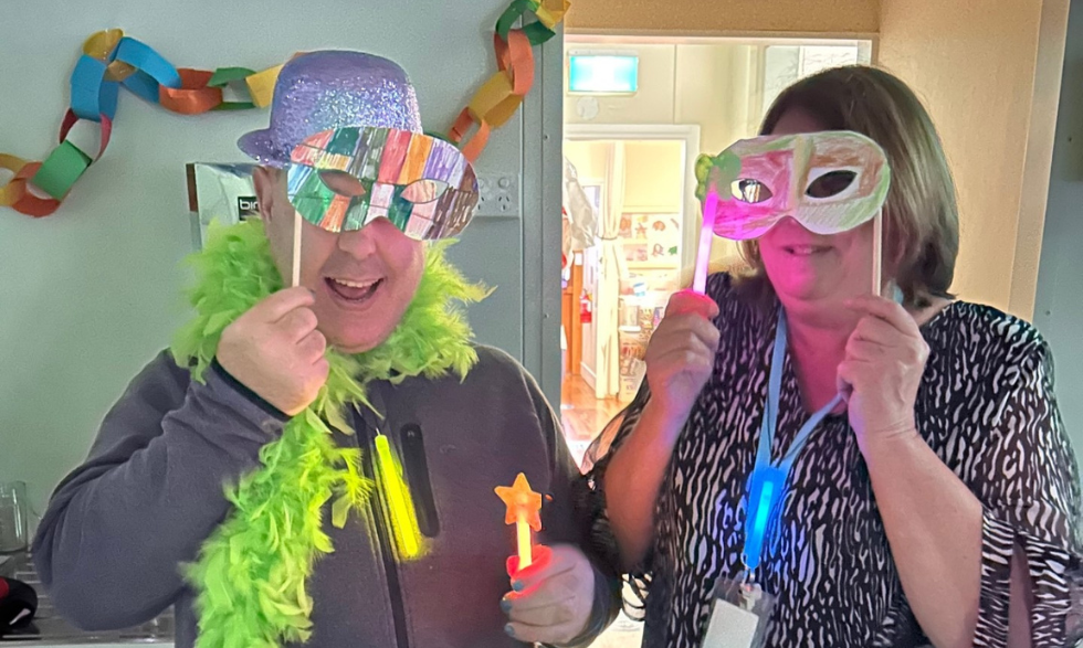 Two clients try on colourful masks while wearing glow sticks